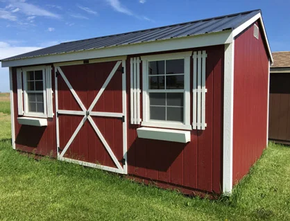 A red shed with windows and shutters on the side.